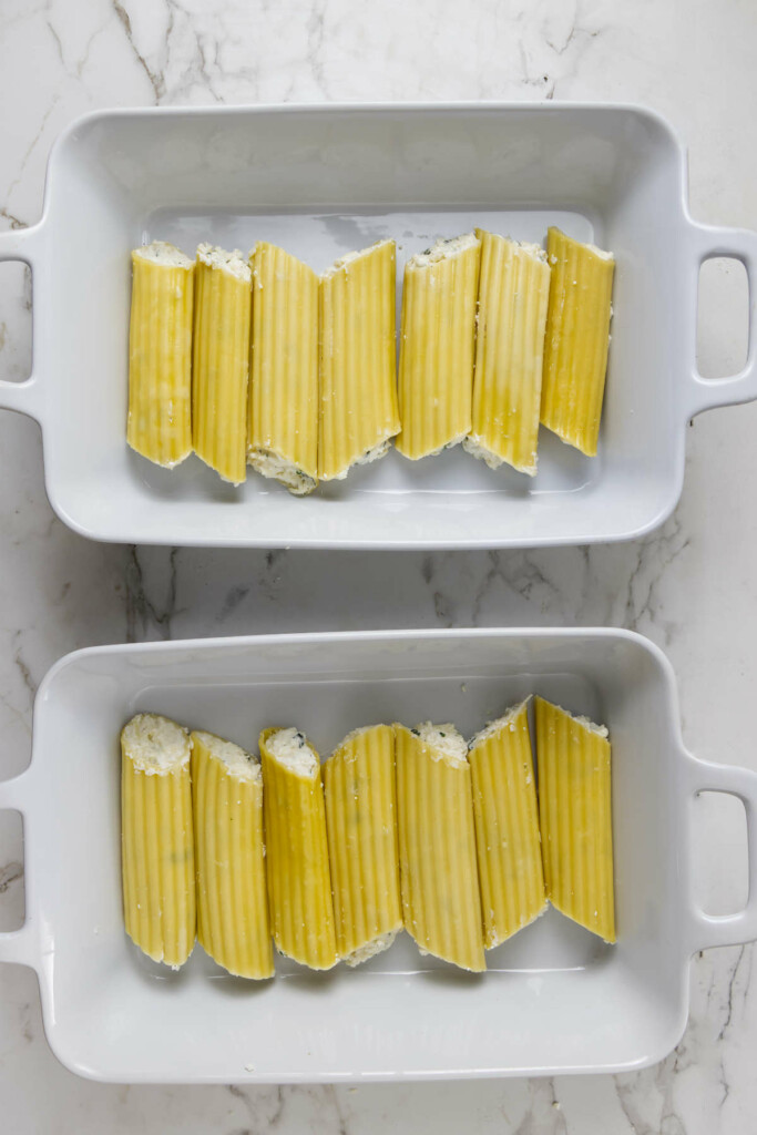 Stuffed manicotti split between two baking dishes before baking—a flexible baked pasta dinner option.