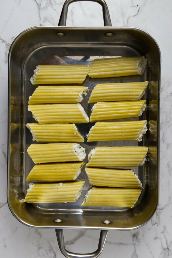 Fourteen manicotti arranged in a large roasting pan with extra room for sauce—perfect for a saucy baked pasta dish.