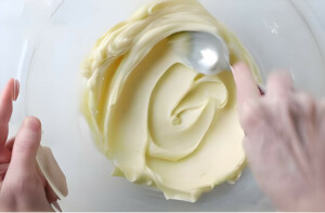 Smoothing thick white chocolate ganache in a bowl.