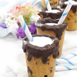 Chocolate cookie cups with milk and straws, flowers in the background.