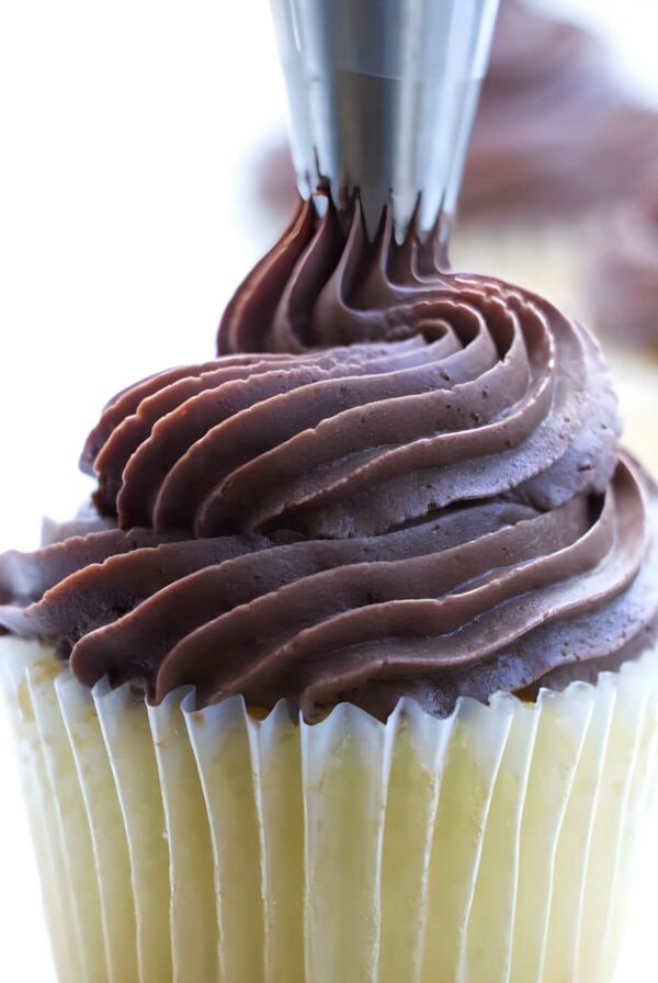 Close-up of chocolate cream cheese frosting piped onto a vanilla cupcake.