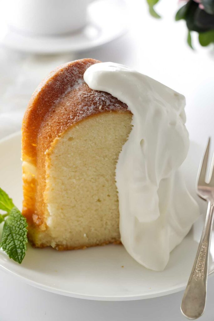 Slice of bundt pound cake with whipped cream and fork.