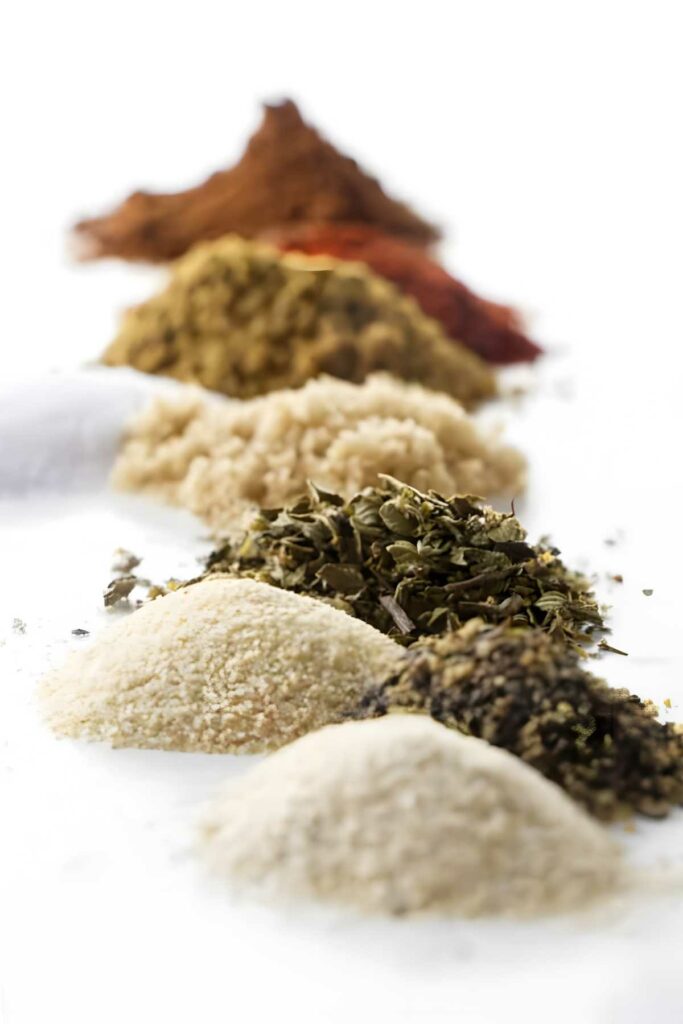 Mounds of ground spices and herbs arranged on counter.