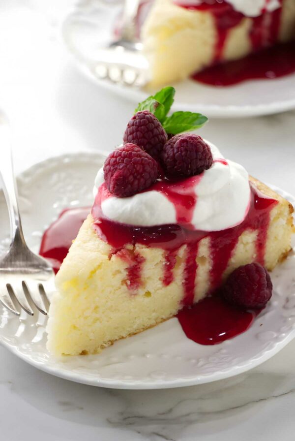 Lemon ricotta cake with whipped cream, raspberry sauce, and fork.