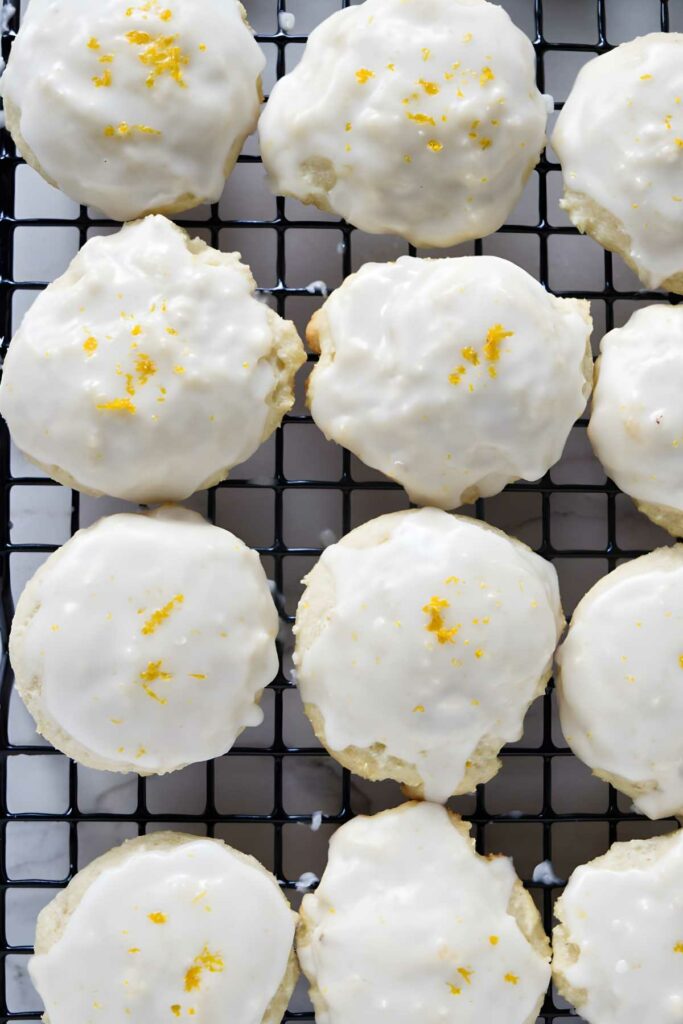Lemon ricotta cookies with white icing on cooling rack.