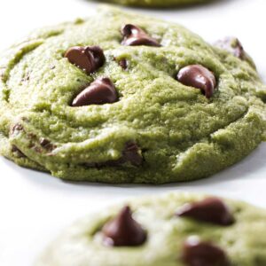 Close-up of matcha chocolate chip cookies with melted chips on white background.