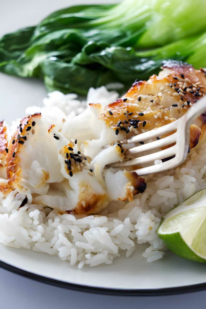Fork flaking miso sea bass on rice with lime and greens.