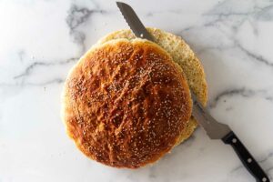 Slicing a round muffeletta bread loaf in half.