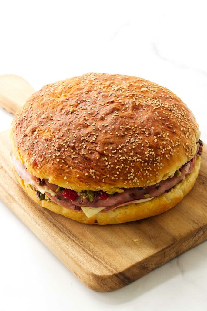 A large mufulleta picnic sandwich on a cutting board.