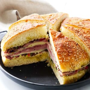 An Italian olive sandwich on a black platter.