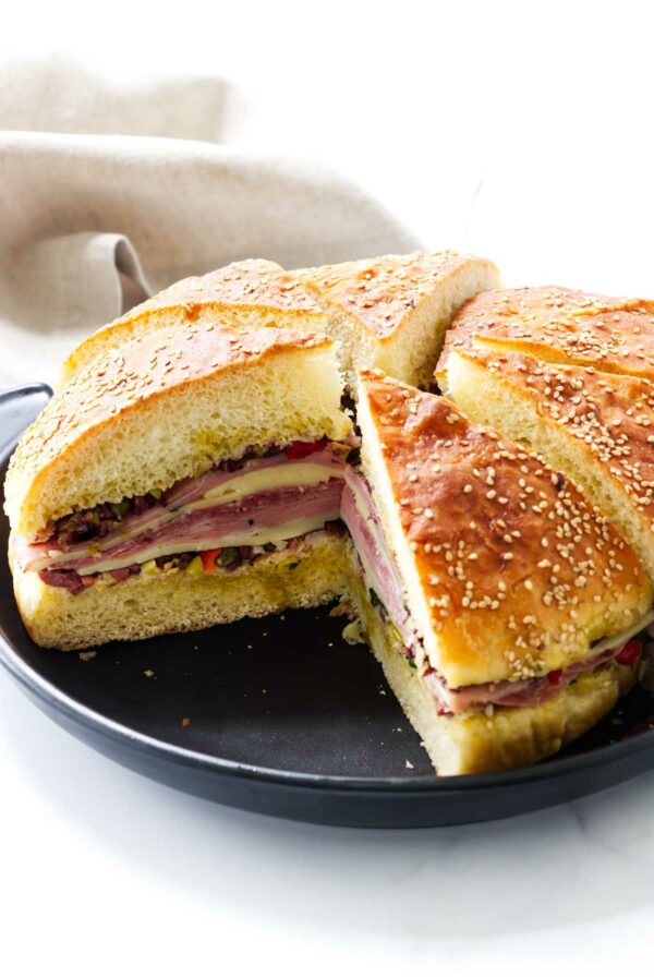 An Italian olive sandwich on a black platter.