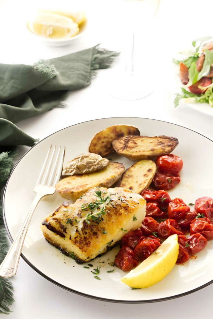 Skillet chilean bass fish with potatoes, tomatoes, herbs.