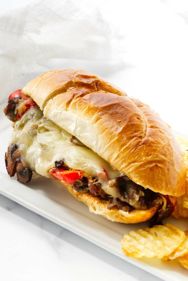 A philly steak and cheese sandwich on a white platter.