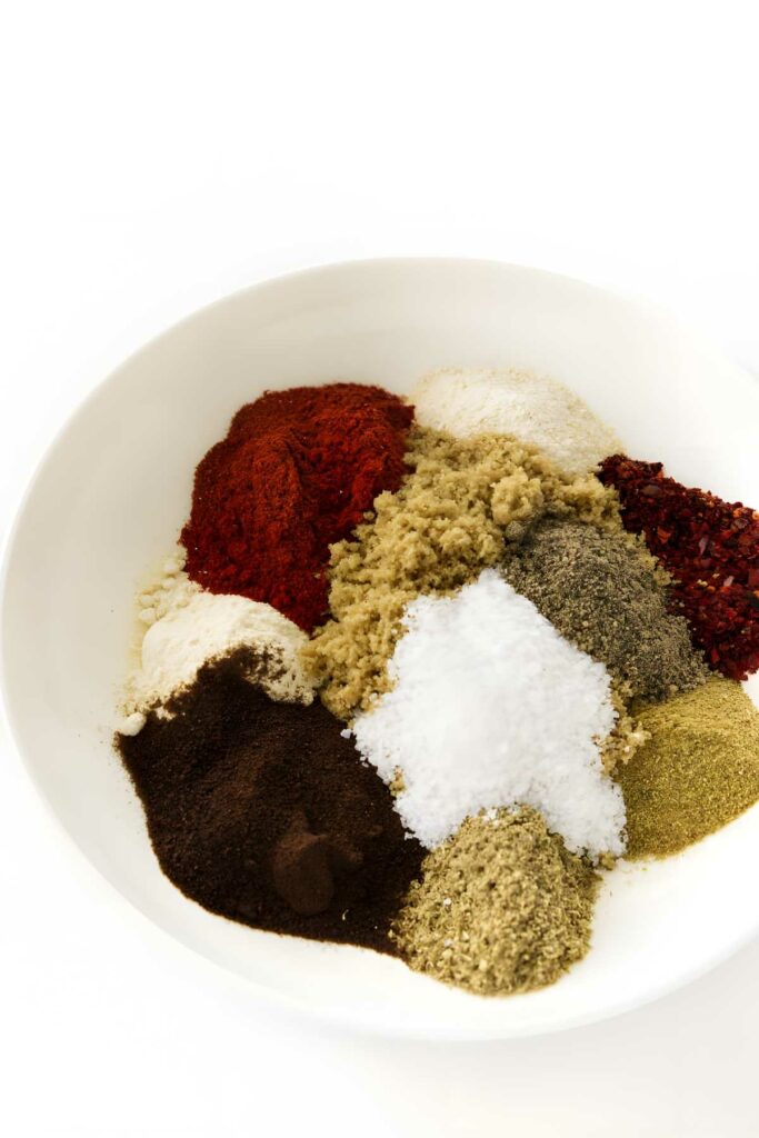 White bowl with assorted colorful spice powders.