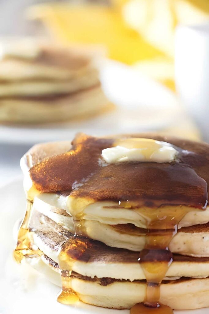 Close-up of lemon ricotta sourdough pancakes with melting butter and syrup.