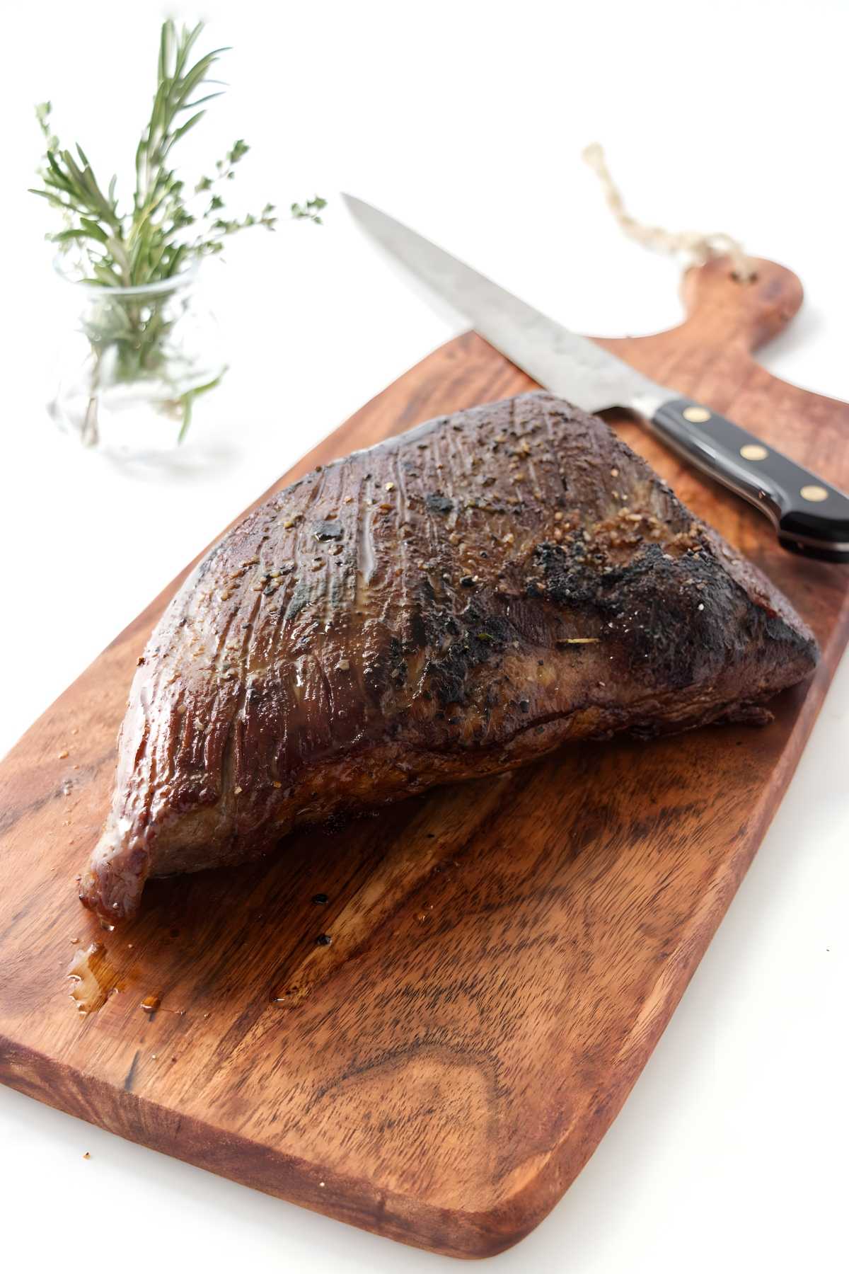 Sous vide tri tip beef on cutting board with knife.