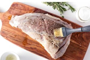 A tri tip on cutting board, brushed with oil and.