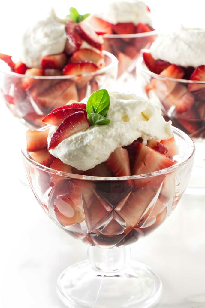 Strawberries and whipped ricotta in glass bowls, topped with mint leaves.