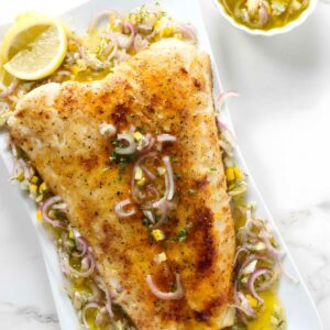 Smoked sea bass fillet with herb topping on platter.