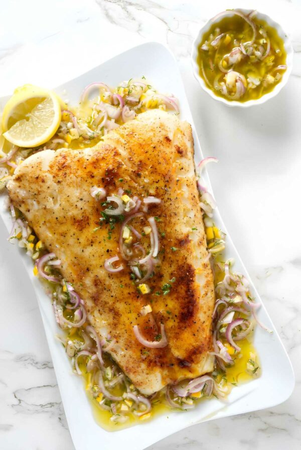 Smoked sea bass fillet with herb topping on platter.