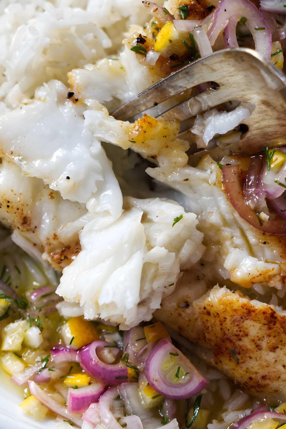 Flaky smoked sea bass with a fork.