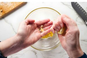 Hand squeezing lemon juice into bowl.