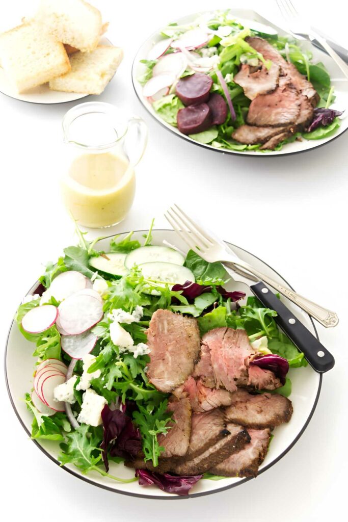 A steak salad made with leftover tri tip on a white counter.