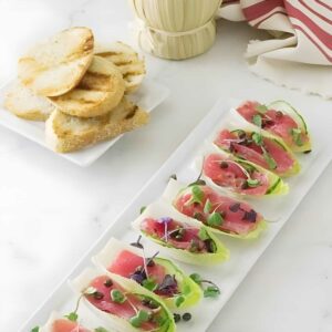 Ahi tuna tartare on endive with toast, bottle in background.