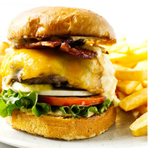 A bacon cheeseburger on a plate with French fries.