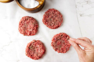 Adding salt to hamburger patties.