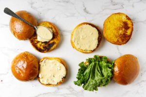 Adding special sauce to toasted hamburger buns.