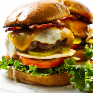Two cheeseburgers loaded with bacon and veggies.