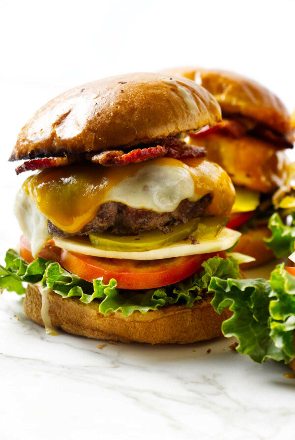 Two cheeseburgers loaded with bacon and veggies.