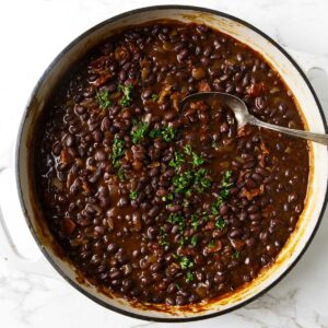 BBQ black beans in a skillet with a spoon.