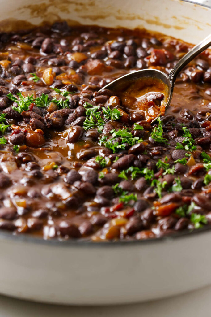 A skillet with bbq black beans topped with parsley.