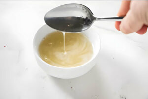 A spoon drizzling dissolved gelatin into a dish.