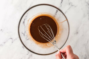 A whisk stirring chocolate mixture in a bowl.