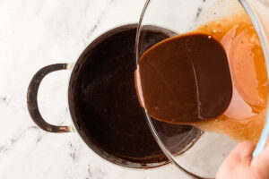Pouring tempered egg yolks into the hot milk mixture.