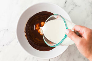 Pouring cream into chocolate ice cream custard.