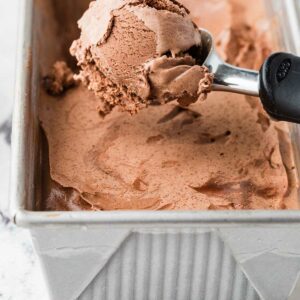 Scooping chocolate ice cream out of a pan.