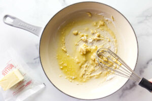 Whisking flour into melted butter on a skillet.
