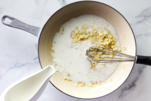 Whisking milk into the butter and flour mixture.
