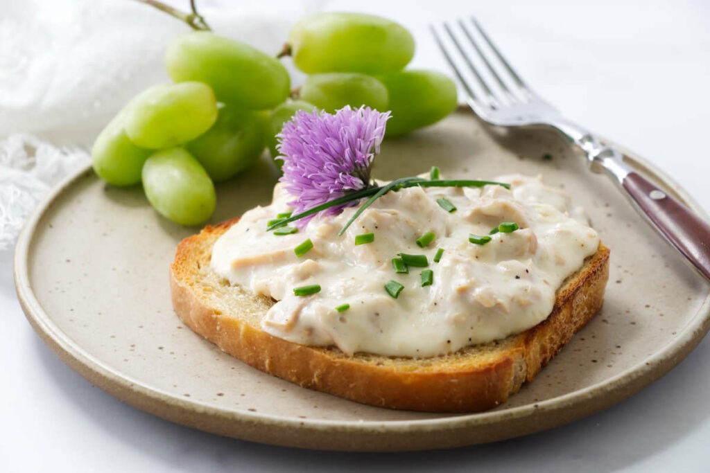 Old fashioned creamed tuna on toasted bread next to grapes.