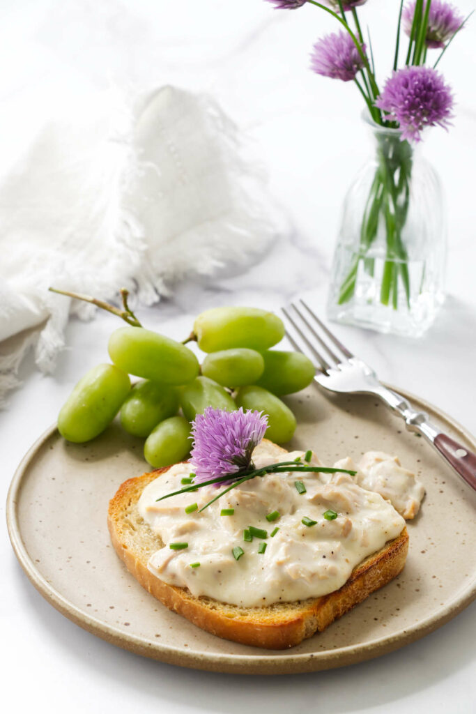 Toast topped with creamed tuna on a plate with grapes.