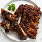 Slow cooker ribs on a plate covered with Dr Pepper bbq sauce.