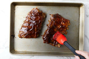 Brushing a barbecue sauce over the slow cooker ribs.