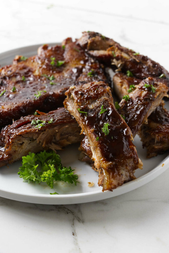 Several ribs on a plate covered in Dr Pepper sauce.