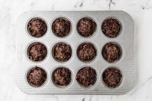 Adding the sourdough chocolate batter to muffin tins.