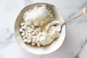combining sour cream, marshmallows and coconut for a fruit salad dressing.