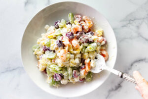 Mixing fresh fruit with a creamy dressing and marshmallows.